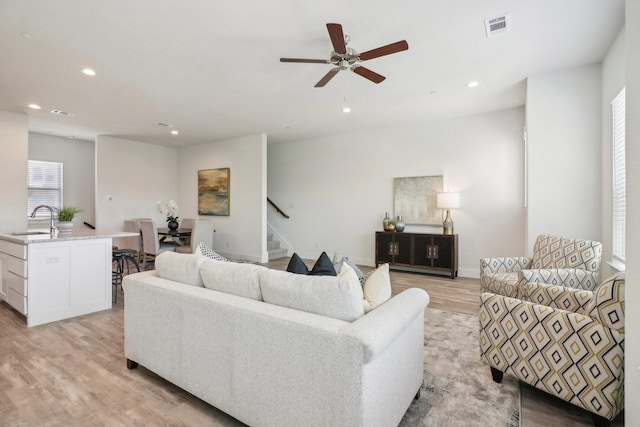 living room featuring ceiling fan, sink, and light hardwood / wood-style flooring