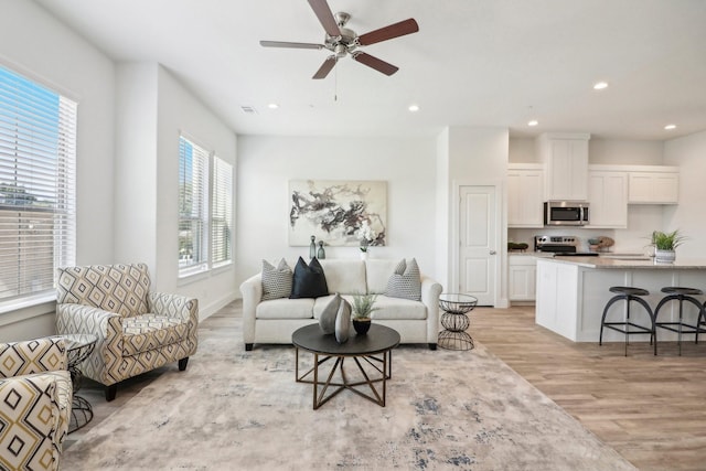 living room with ceiling fan and light hardwood / wood-style flooring