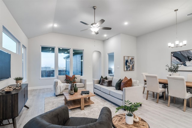 living room featuring lofted ceiling, ceiling fan with notable chandelier, and light wood-type flooring