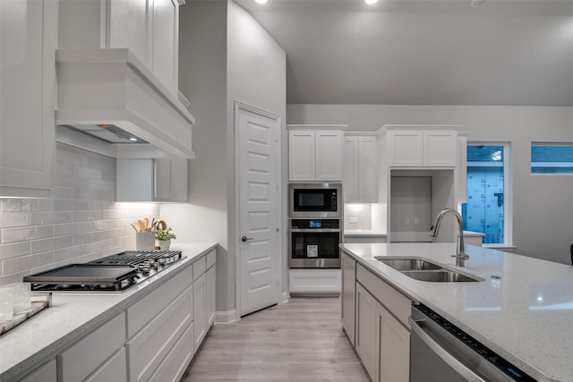 kitchen featuring light stone countertops, stainless steel appliances, white cabinetry, and sink