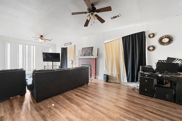 living room featuring hardwood / wood-style flooring, a brick fireplace, and ceiling fan