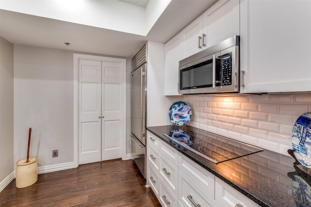 kitchen featuring backsplash, dark stone countertops, white cabinetry, and appliances with stainless steel finishes