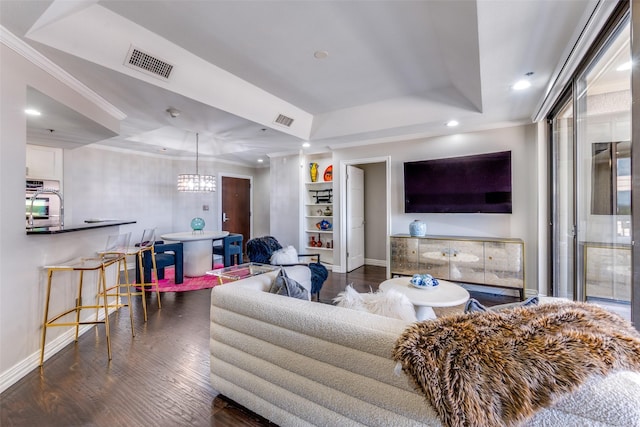 living room featuring dark hardwood / wood-style flooring, a raised ceiling, and ornamental molding