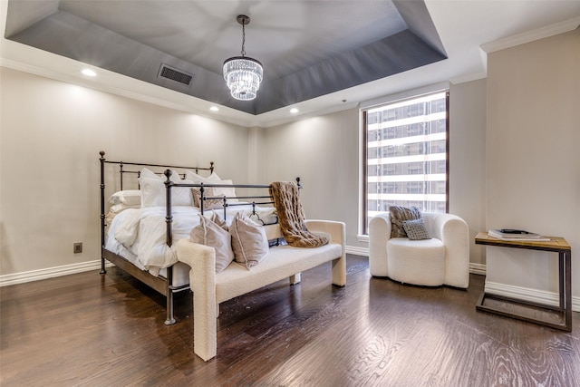 bedroom featuring a chandelier, dark hardwood / wood-style flooring, a raised ceiling, and ornamental molding