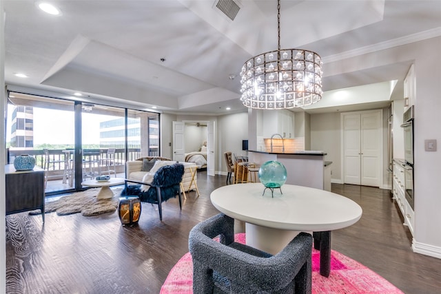 dining space with sink, crown molding, a tray ceiling, dark hardwood / wood-style flooring, and a chandelier