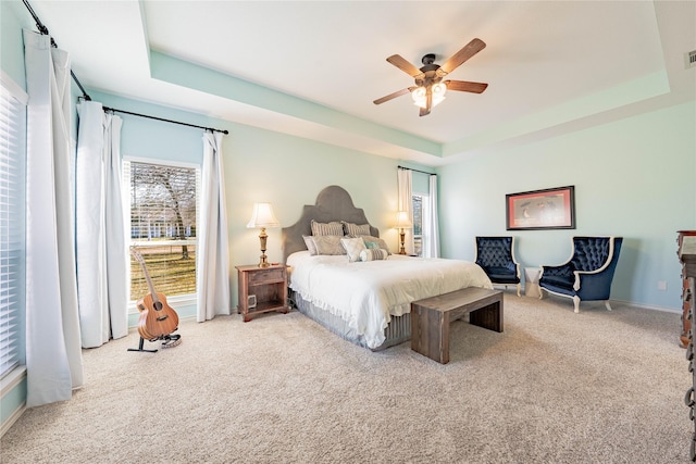 carpeted bedroom with a tray ceiling and ceiling fan