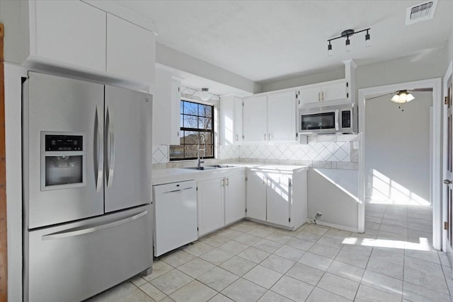 kitchen featuring decorative backsplash, appliances with stainless steel finishes, ceiling fan, sink, and white cabinetry