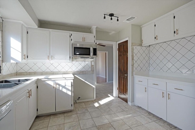 kitchen featuring white dishwasher, decorative backsplash, ceiling fan, and white cabinetry