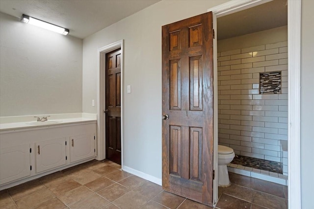 bathroom featuring tiled shower, vanity, and toilet