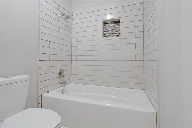 bathroom featuring tiled shower / bath combo and toilet