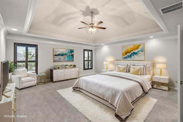 carpeted bedroom featuring ceiling fan, a tray ceiling, and multiple windows