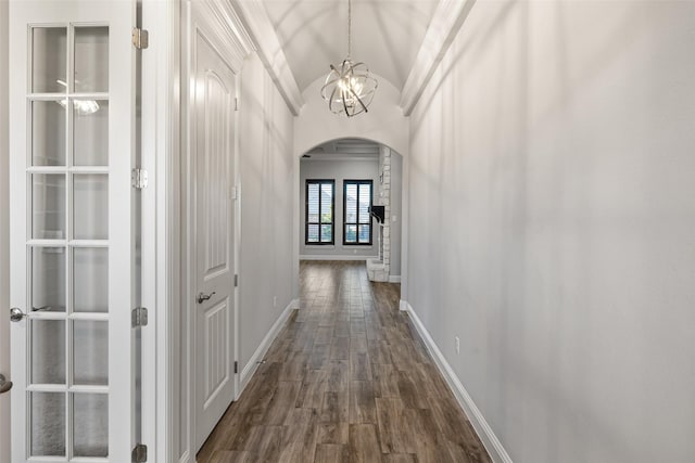 corridor featuring dark wood-type flooring, lofted ceiling, ornamental molding, and a notable chandelier