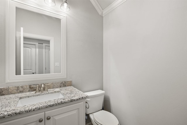 bathroom featuring toilet, ornamental molding, and vanity