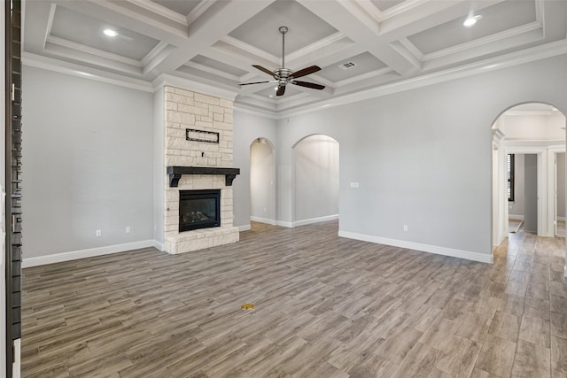 unfurnished living room featuring coffered ceiling, hardwood / wood-style floors, ceiling fan, a fireplace, and crown molding