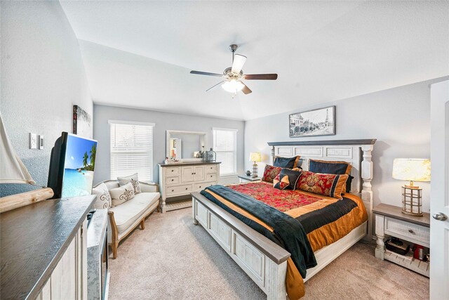 bedroom with ceiling fan, lofted ceiling, light carpet, and ensuite bath