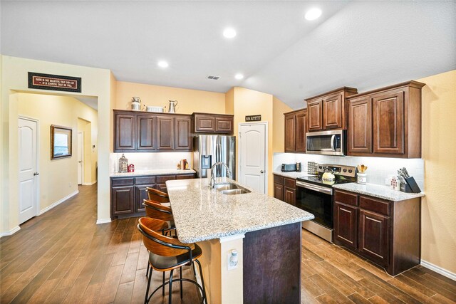 kitchen featuring sink, vaulted ceiling, light stone countertops, dark hardwood / wood-style flooring, and stainless steel appliances