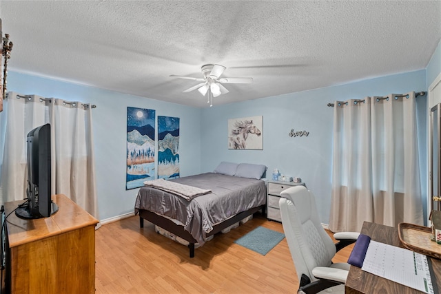 bedroom with ceiling fan, light hardwood / wood-style floors, and a textured ceiling