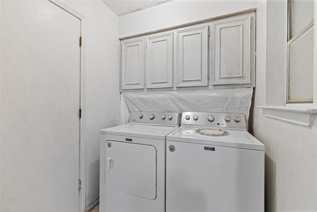 washroom featuring washing machine and dryer, cabinets, and a textured ceiling