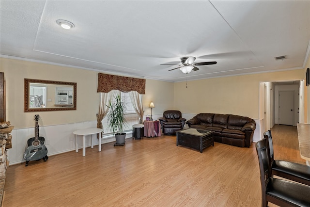 living room with ceiling fan, a textured ceiling, ornamental molding, and light hardwood / wood-style floors