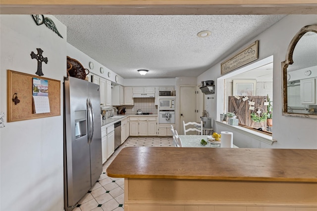 kitchen featuring a textured ceiling, stainless steel appliances, decorative backsplash, sink, and kitchen peninsula