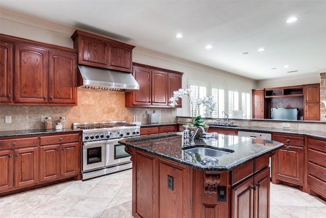 kitchen featuring sink, ventilation hood, a center island with sink, double oven range, and decorative backsplash