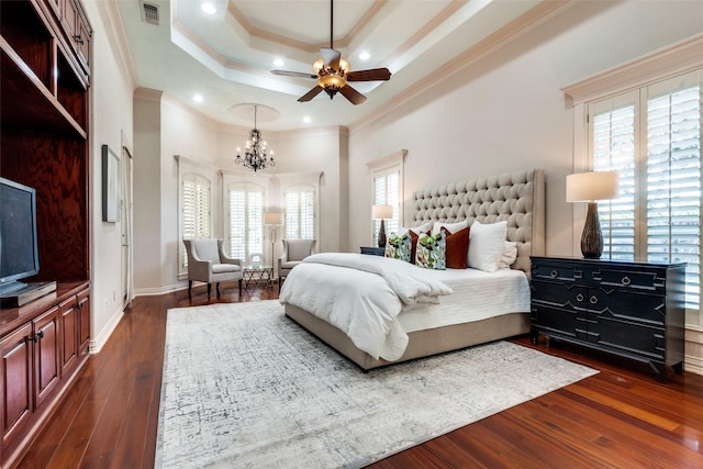 bedroom featuring a tray ceiling, ceiling fan with notable chandelier, dark wood-type flooring, and crown molding