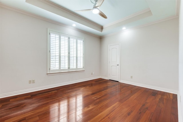 empty room featuring a tray ceiling, dark wood-type flooring, and ceiling fan