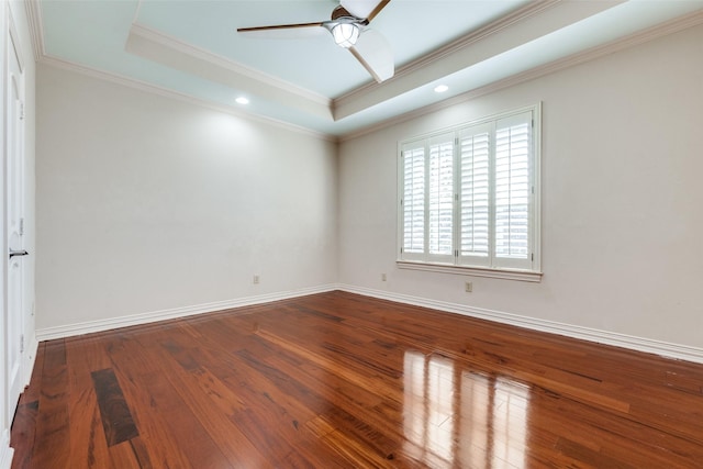 empty room with crown molding, hardwood / wood-style flooring, a raised ceiling, and ceiling fan