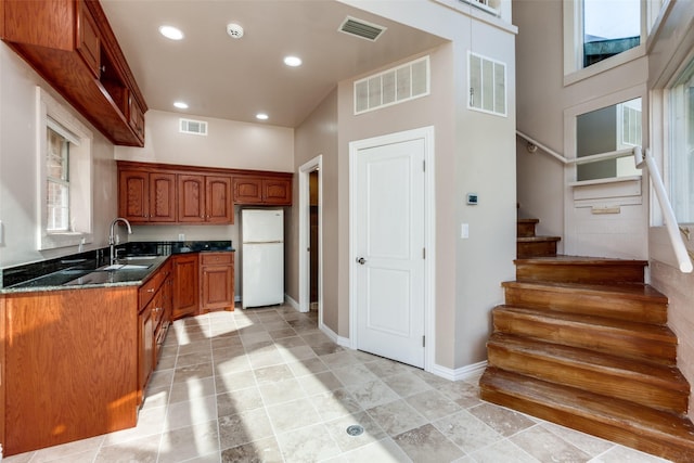 kitchen with white fridge, sink, and dark stone counters