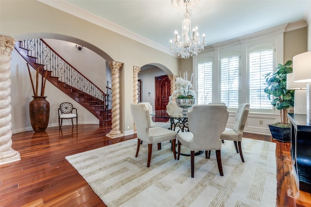 dining space with ornate columns, crown molding, hardwood / wood-style floors, and an inviting chandelier