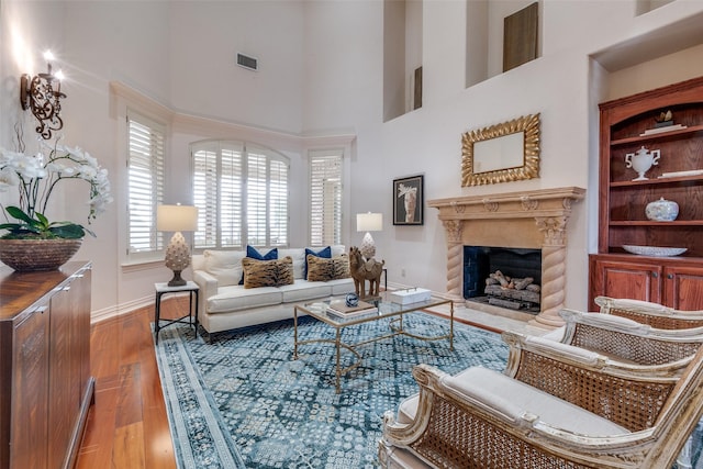 living room featuring hardwood / wood-style floors, a high end fireplace, and a high ceiling