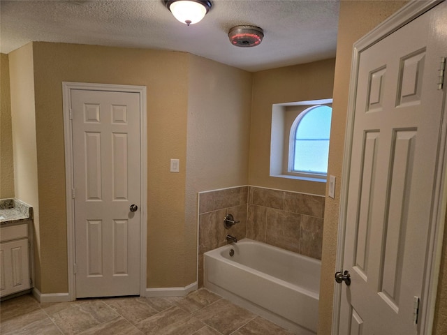 bathroom with tile patterned floors, vanity, a bath, and a textured ceiling