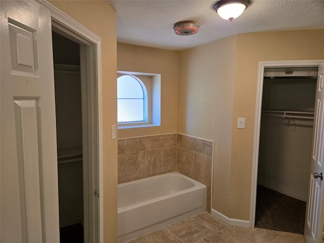 bathroom with a bathing tub, tile patterned flooring, and a textured ceiling