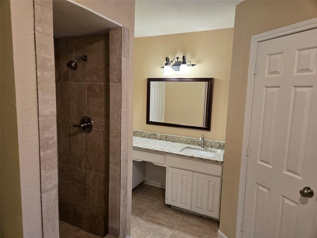 bathroom featuring a tile shower, tile patterned floors, and vanity