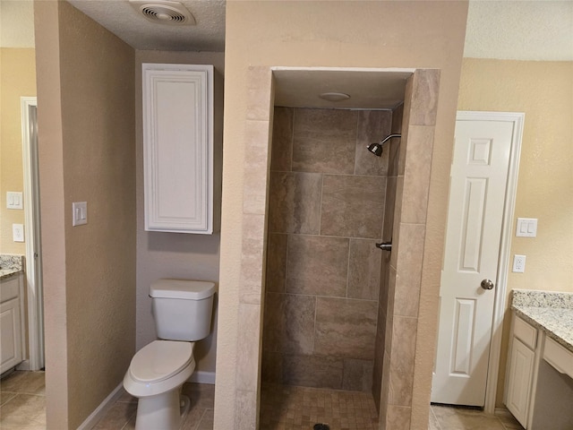 bathroom with tiled shower, tile patterned floors, vanity, and toilet