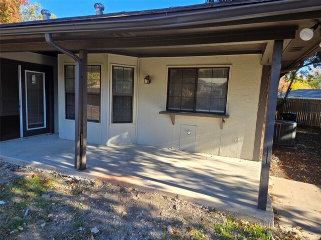 view of exterior entry with a patio and central AC unit