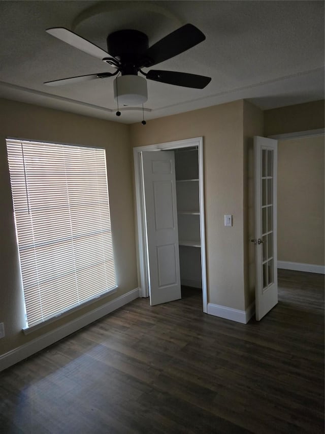 unfurnished bedroom with ceiling fan, french doors, dark wood-type flooring, and a closet