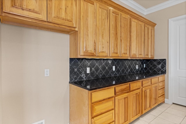 kitchen with backsplash, ornamental molding, dark stone counters, and light tile patterned floors