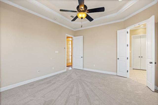 unfurnished bedroom featuring a tray ceiling, ceiling fan, crown molding, and light colored carpet