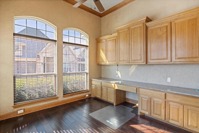 unfurnished office featuring built in desk, ornamental molding, dark hardwood / wood-style floors, and ceiling fan