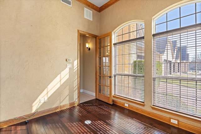 spare room featuring hardwood / wood-style flooring, a towering ceiling, crown molding, and a wealth of natural light