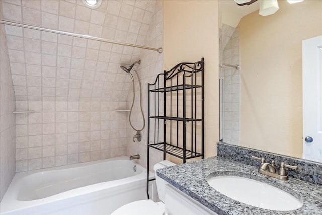 full bathroom featuring vanity, tiled shower / bath, and toilet