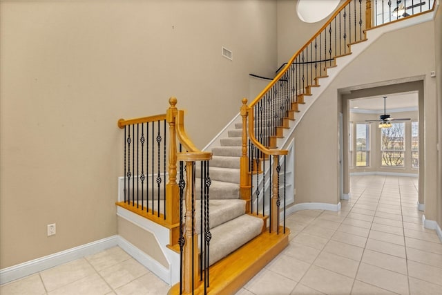 stairway featuring a towering ceiling, tile patterned floors, and ceiling fan