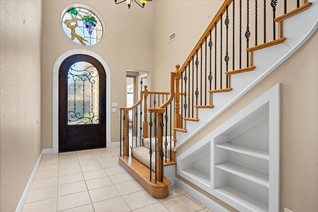 tiled entrance foyer with a chandelier and a high ceiling