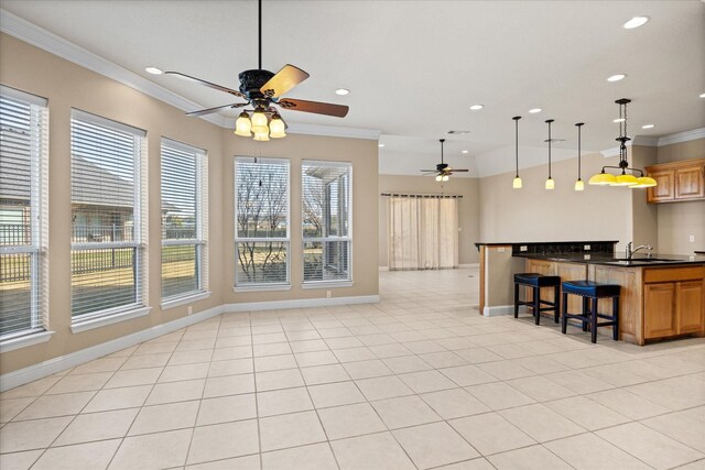 kitchen with a breakfast bar, sink, hanging light fixtures, ornamental molding, and light tile patterned flooring