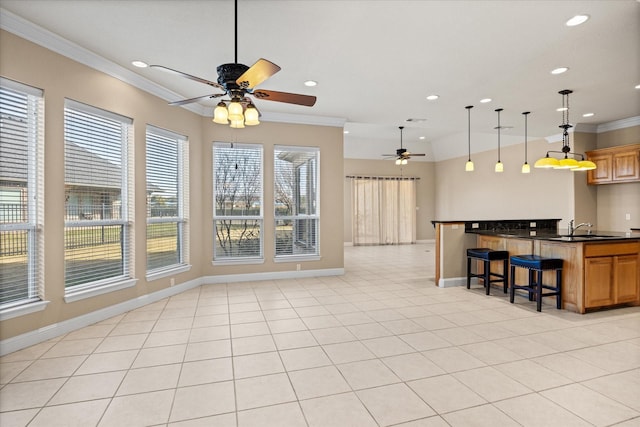 kitchen featuring sink, a kitchen bar, hanging light fixtures, light tile patterned floors, and crown molding