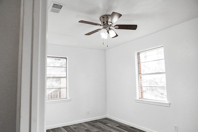 spare room featuring a wealth of natural light, ceiling fan, and dark hardwood / wood-style floors