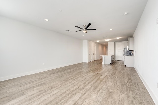 unfurnished living room with ceiling fan, sink, and light hardwood / wood-style floors