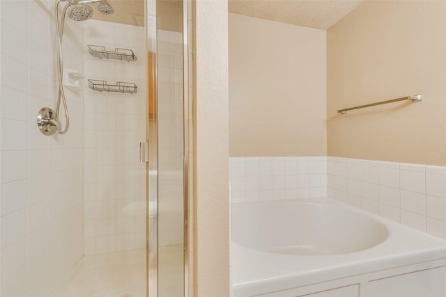 bathroom with a textured ceiling and shower with separate bathtub