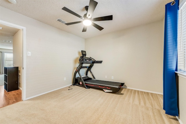 workout room with a textured ceiling, ceiling fan, and light carpet